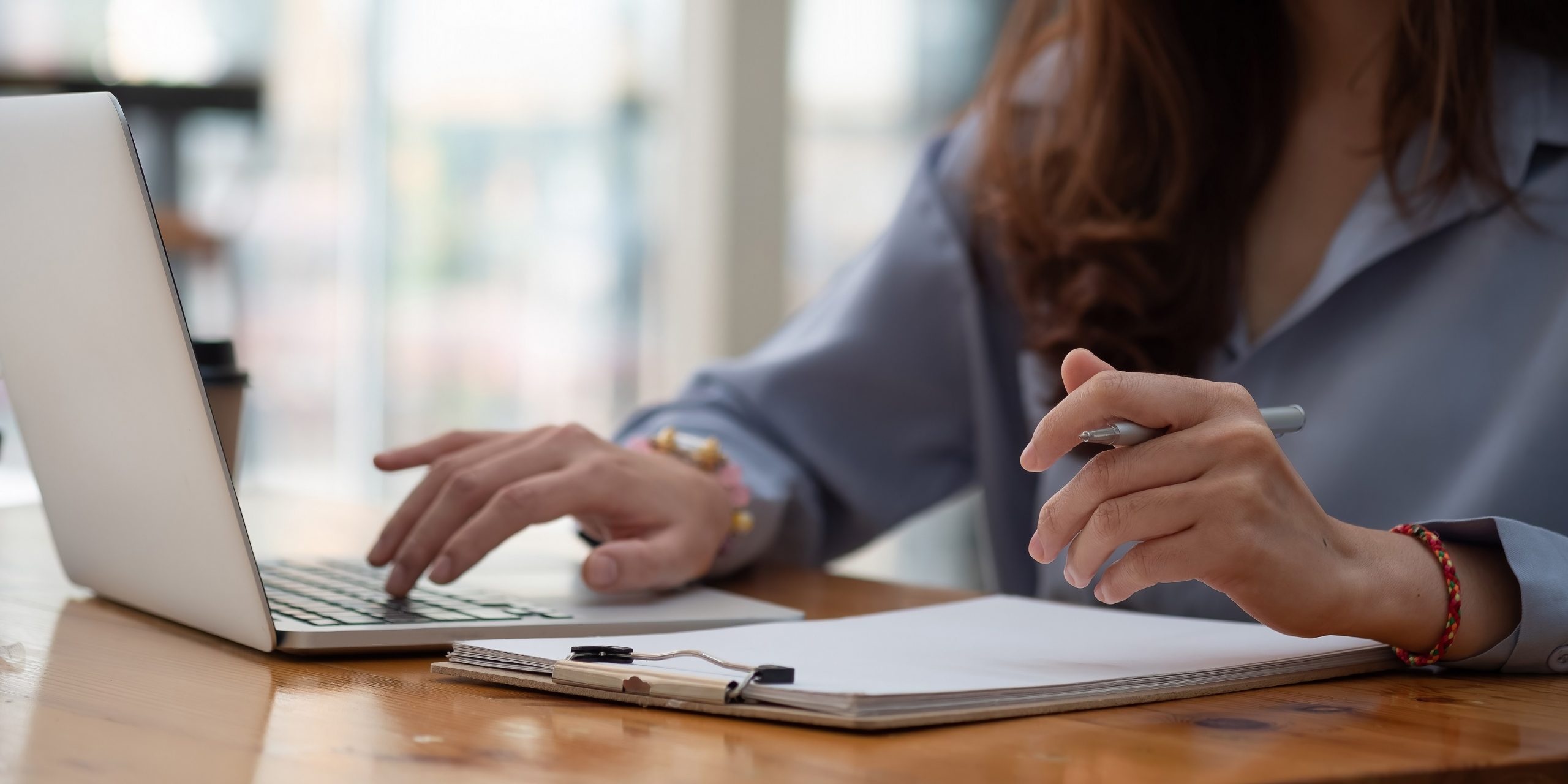 young woman taking notes on a notepad next to laptop