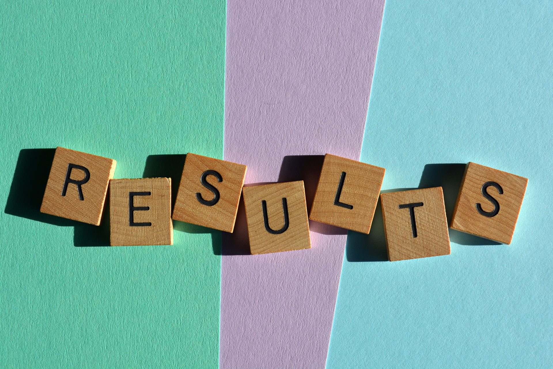 The word "Results" spelled out with wooden alphabet letters isolated on pastel background