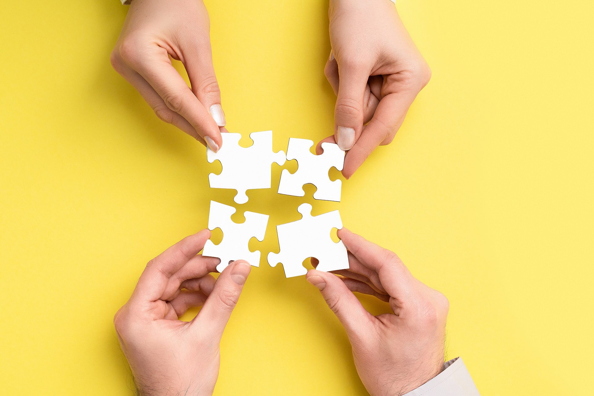 Two pairs of hands trying to fit jigsaw pieces together, symbolizing the power of working together with Emercury to craft strategies