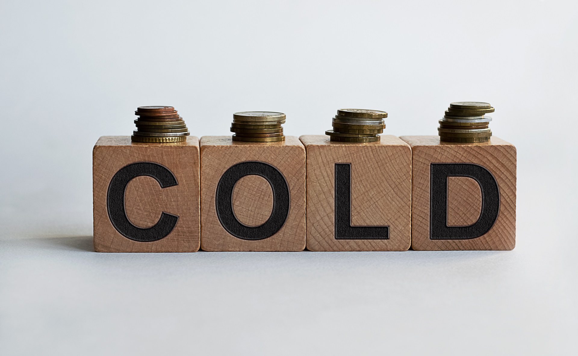 Wooden blocks spelling the word "cold" with stacks of coins on top representing an email list hygiene concept.