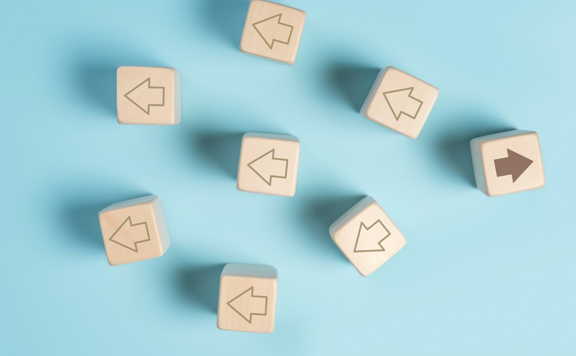 Think different concept, Individual and standing out from the crowd, Wooden block with arrow on pastel blue background, Unique attitude, Opportunities in different directions, Solution, Strategy