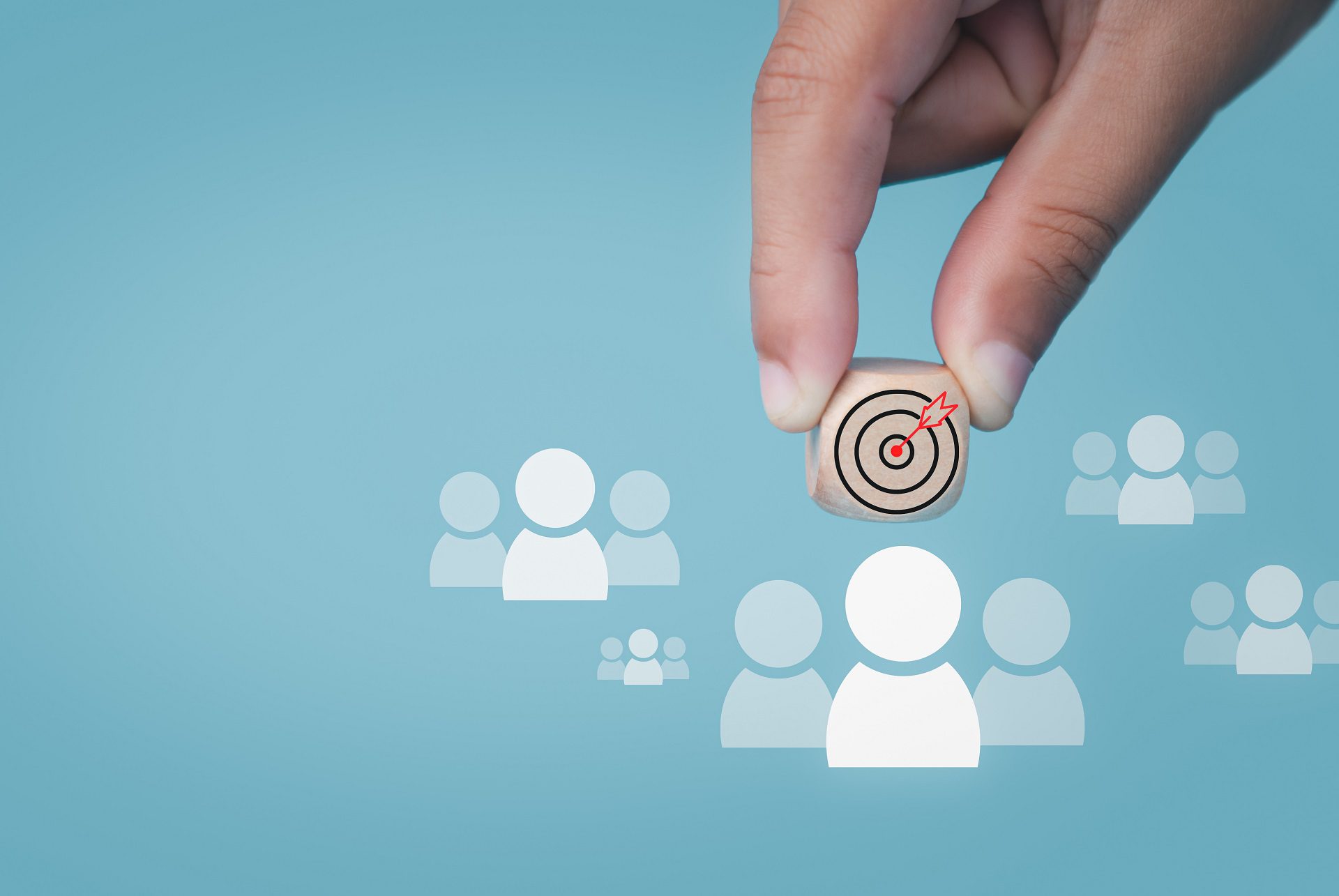 Human hand holds a dart board icon drawn on a wooden block and connects to a target customer on a light blue background It represents the selection of business goals. Marketing plans and strategies.